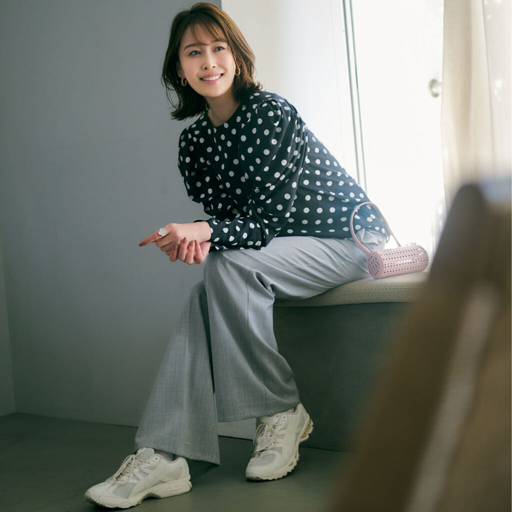 ドットブラウスにグレーのスラックスと白スニーカーのコーデ