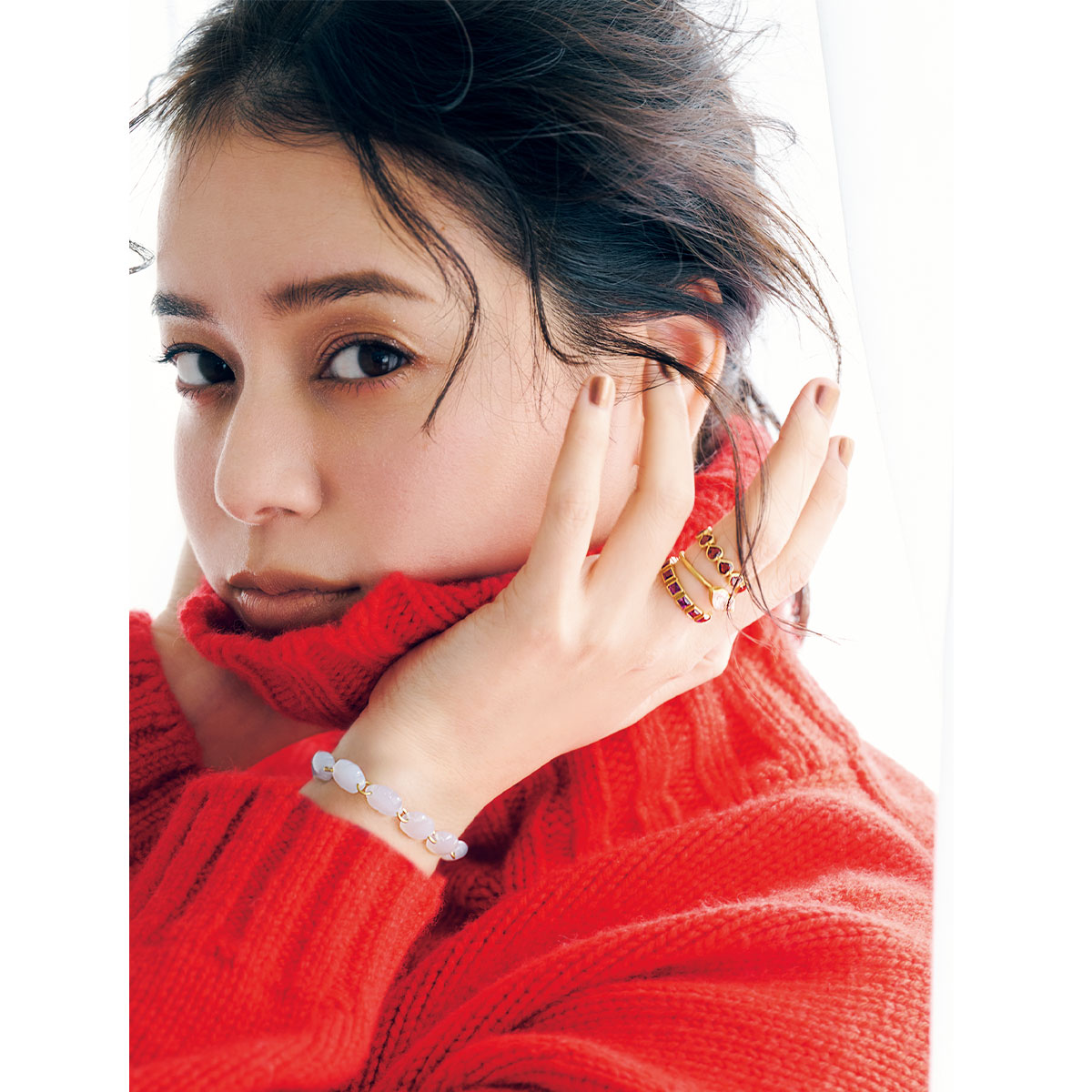 赤のタートルネックを着てマリーエレーヌドゥタイヤックのカラーストーンのブレスレットや指輪を重ねづけした岸本セシルさん