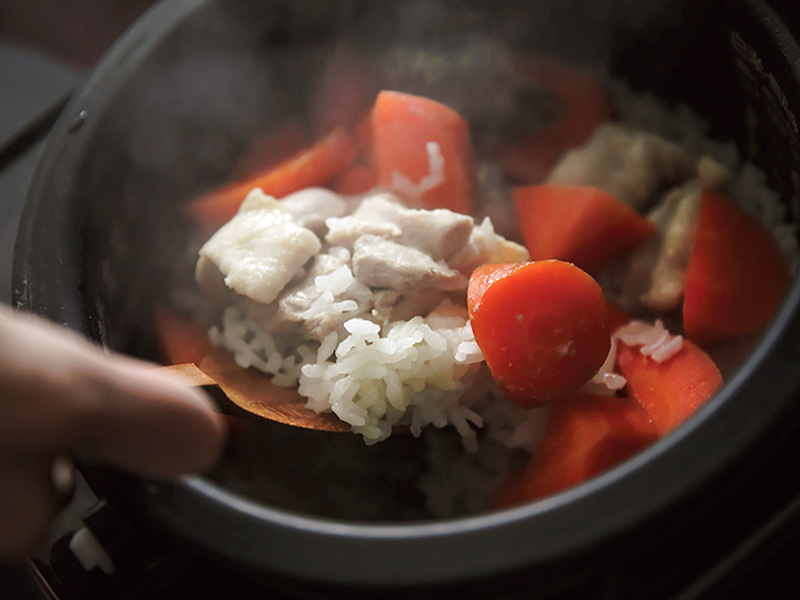 炊飯器からにんじんと鶏の炊き込みごはんをすくうところ