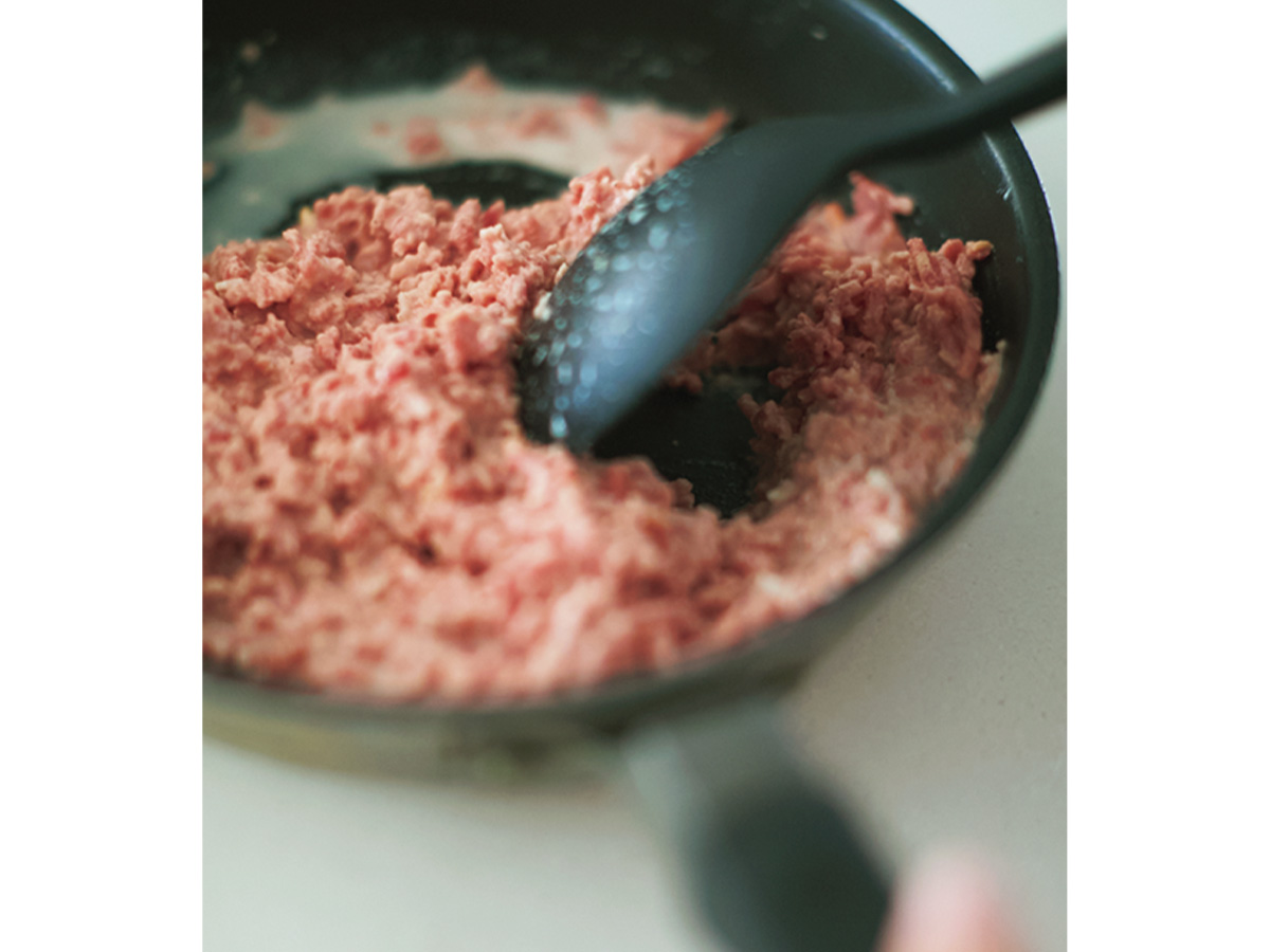 フライパンの上でヘラで肉だねを混ぜているところ