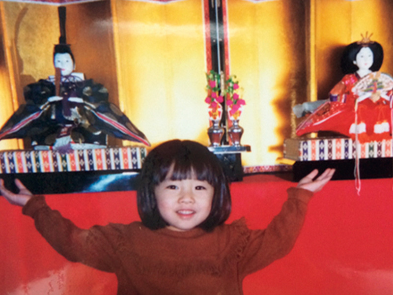 お雛様の前でポーズをとる幼少期の美馬アンナさん
