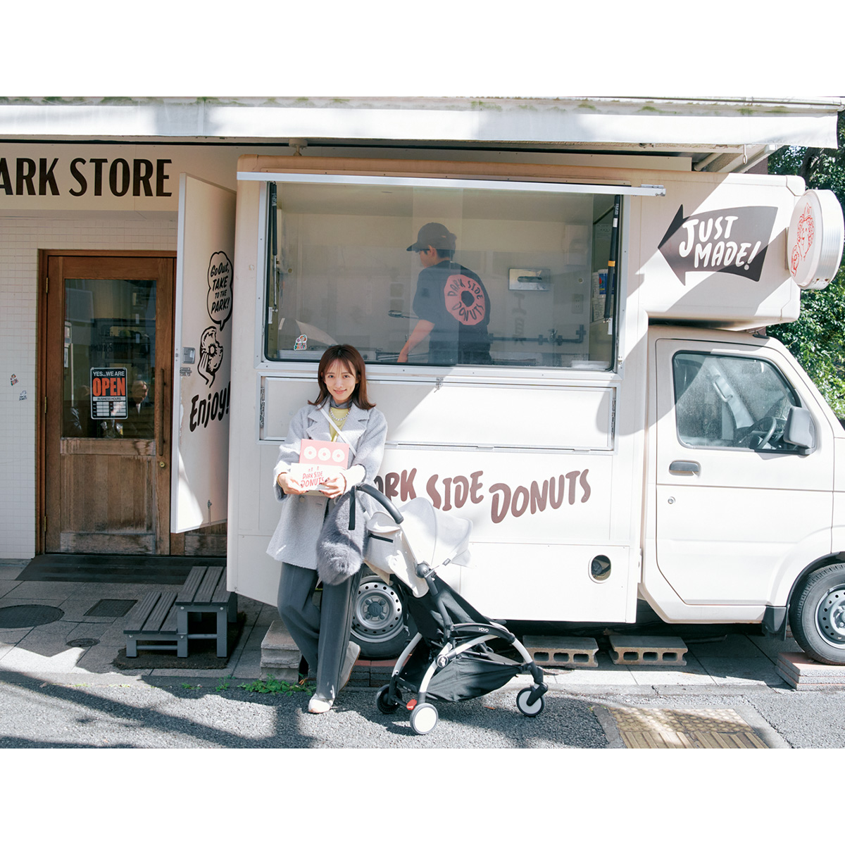 夏菜さんがテイクアウトのドーナツの箱を持って店前にたたずむ様子