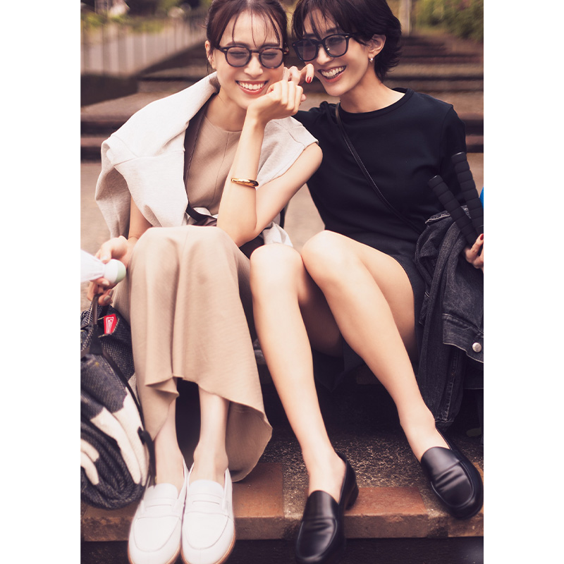 ベージュのワンピースにスウェットを肩掛けして白のローファーを履いた笹川ゆりさんと黒トップスとショートパンツに黒のローファーを履いた神山まりあさん