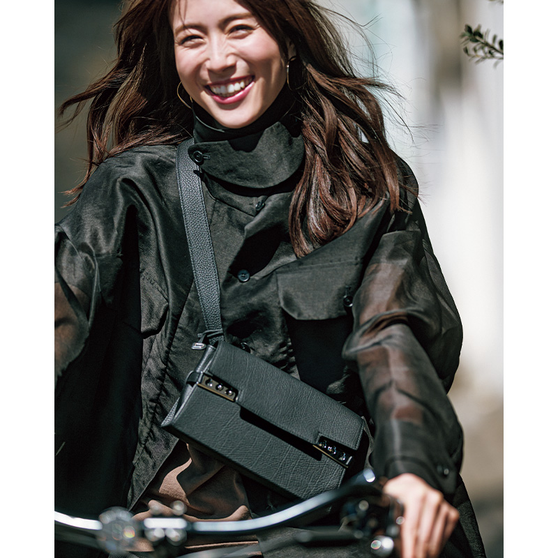 黒のシアージャケットに斜めがけバッグを持って自転車に乗る笹川友里さん