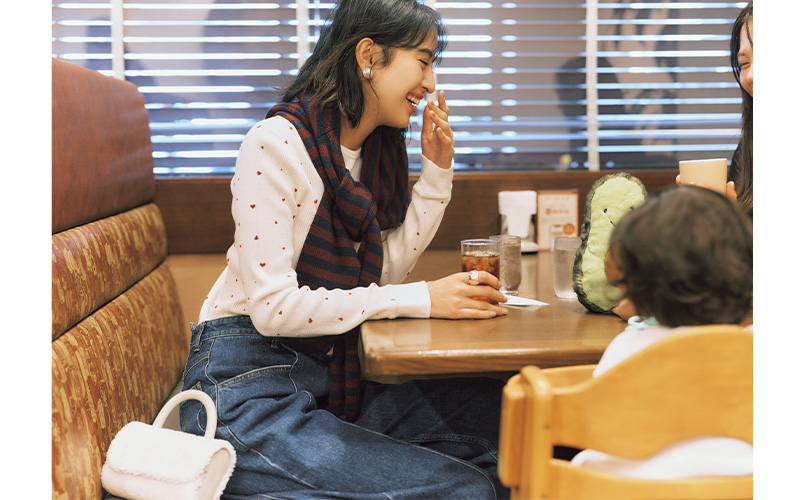 小さなハート柄のサーマルトップスにボーダーニットを肩掛けしてデニムを履いたママ