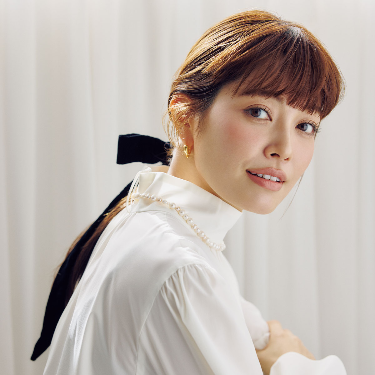 白ブラウスに黒リボンをつけたひとつ結びをした垣内彩未さん