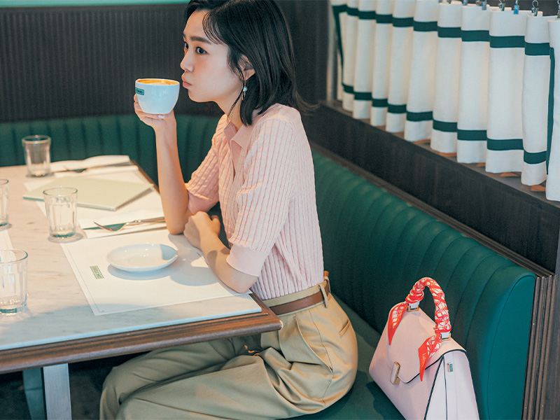 ピンクのポロニットとチノパンのコーデでお茶をする桐谷美玲さん