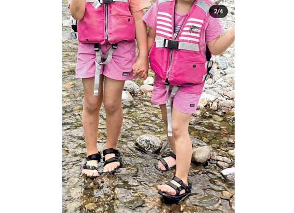 ピンクのライフジャケット着た幼い姉妹が、山のほうの川で遊んでいる