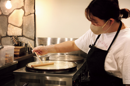 クレープスノカオイ成城店の店内で、クレープを焼いている女性