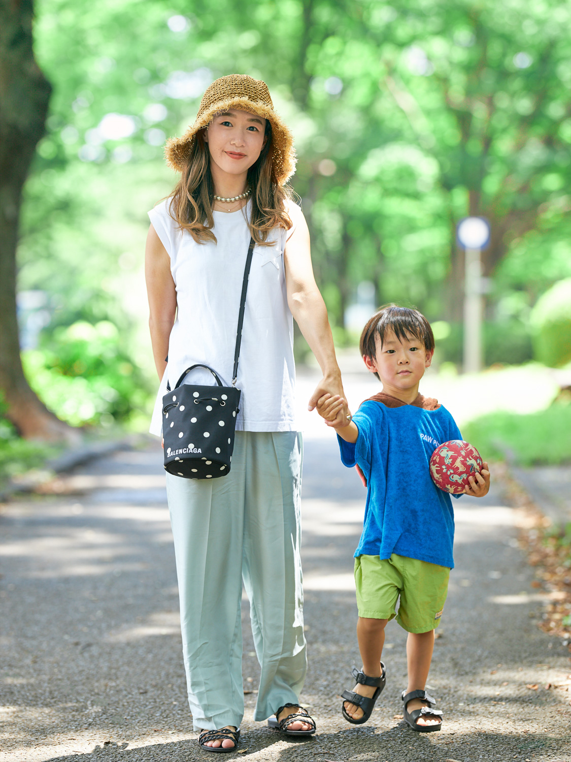 白ノースリーブTシャツ×エメラルドグリーンパンツの夏の公園コーデ。