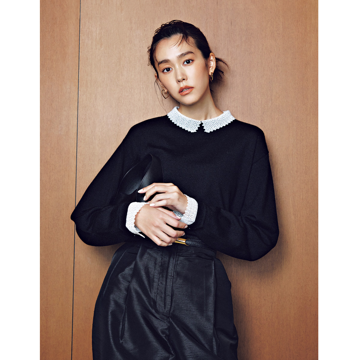 23区のレースの衿つき黒ニットに光沢のある黒パンツを着た桐谷美玲さん