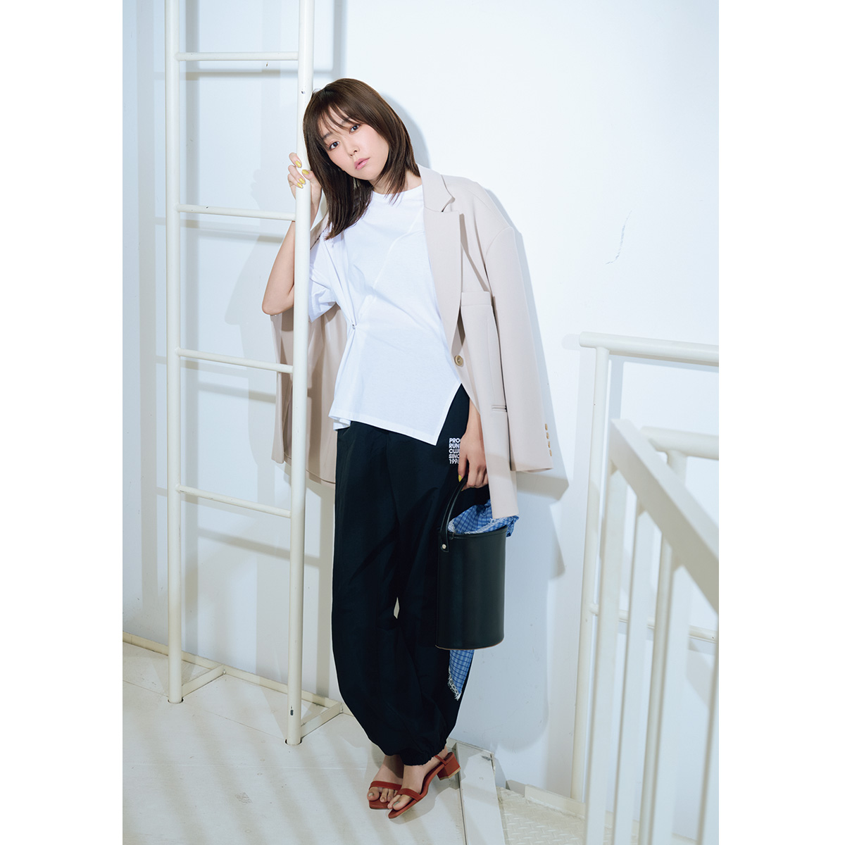 サイドにボタンがあしらわれた白Tシャツとパンツにジャケットを肩掛けしてキレイめに着こなす桐谷美玲さん