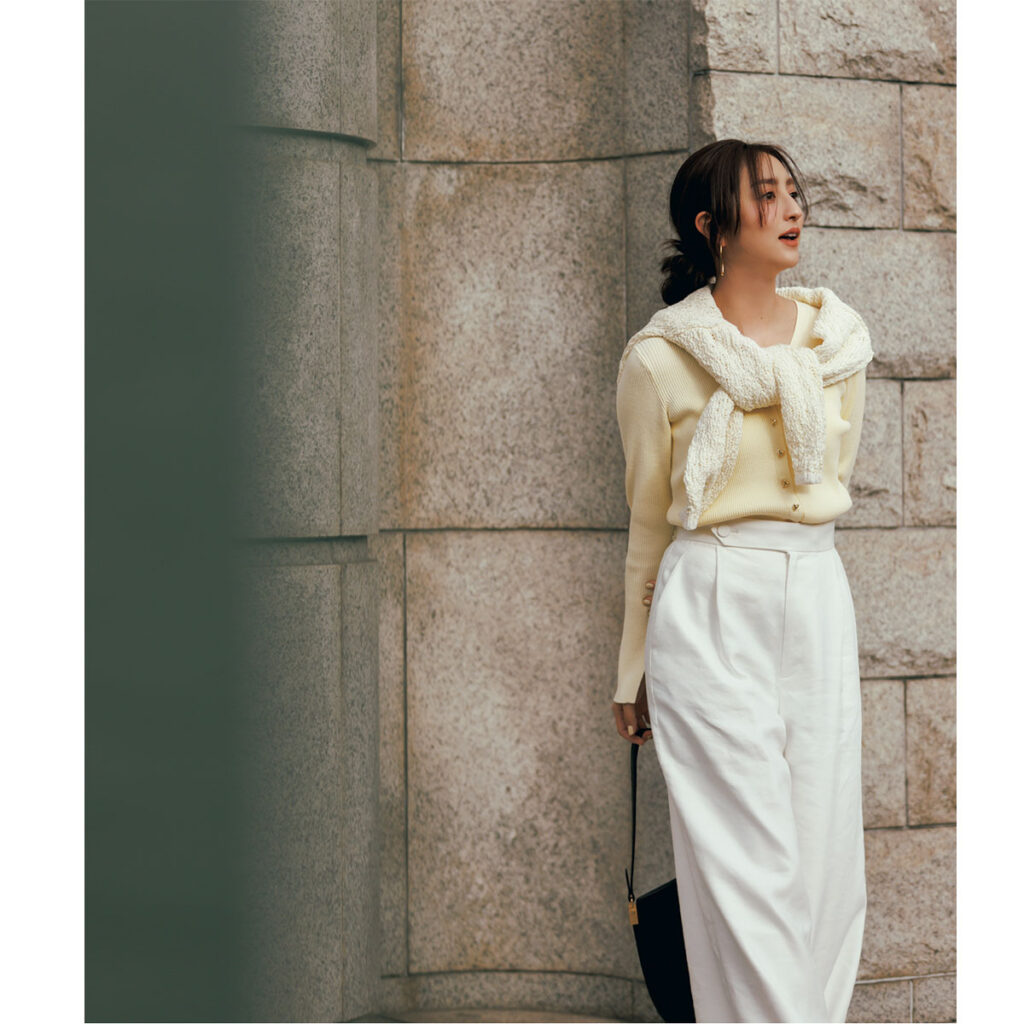 ペールイエローのカーディガンに白のワイドスラックスのコーデ